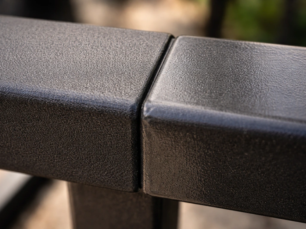 Macro close-up comparing an even baked powder-coat finish and a thin uneven low-quality paint on a metal frame.