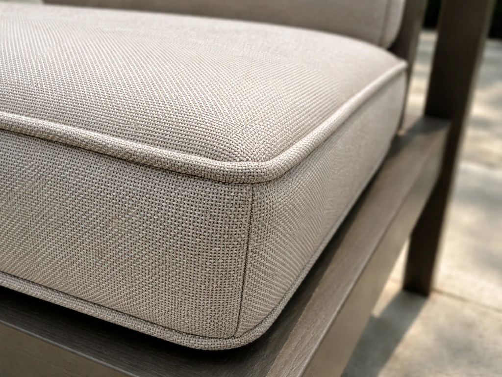 Close-up of outdoor cushion fabric texture and stitching, showing uniform solution-dyed acrylic color.