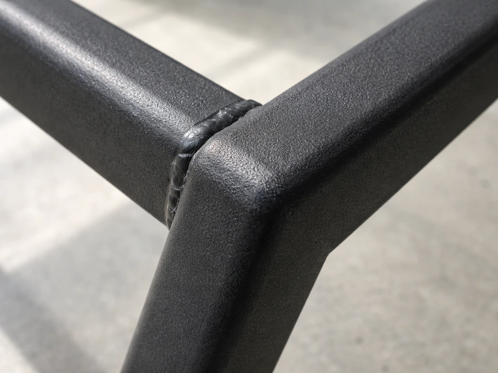 Close-up of a powder-coated metal frame showing clean, uniform weld beads and intact coating at joints